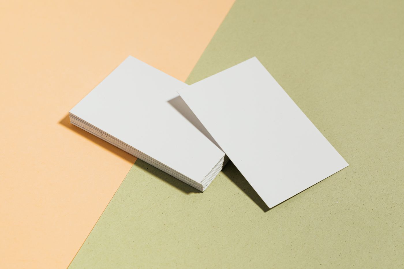 A stack of blank white cards beside a single matching card, on a two-tone paper background.