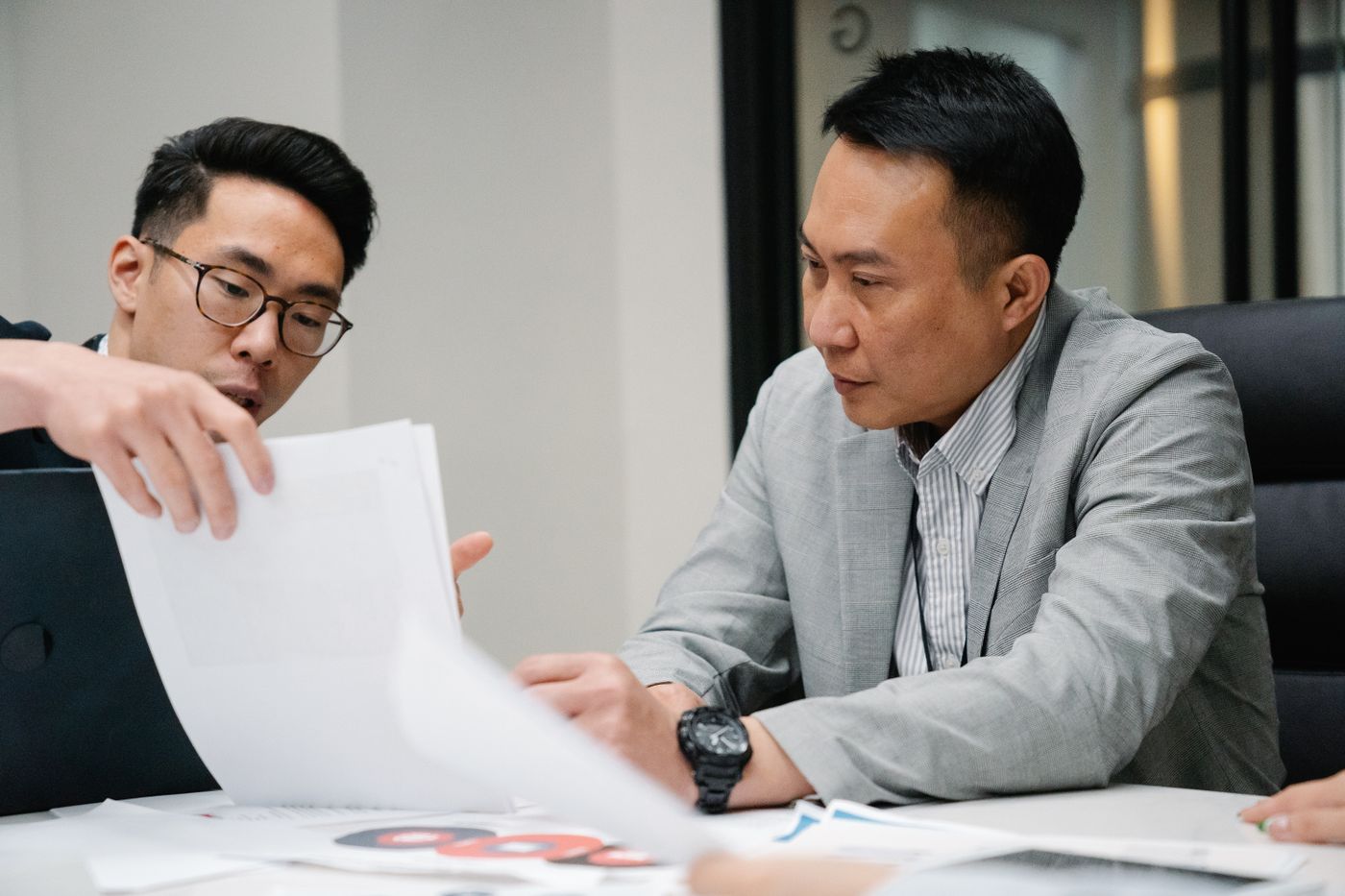 Two colleagues reviewing printed documents together at a desk.