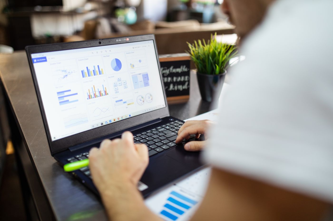 A laptop showing a spreadsheet beside printed columns of figures on a desk.