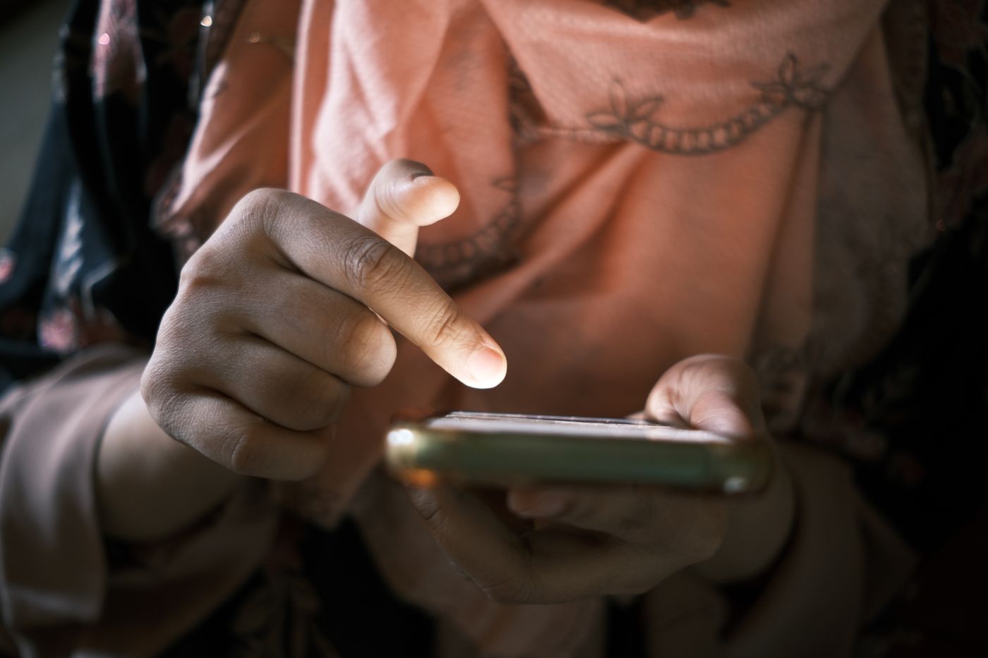 A single finger reaching down to tap the screen of a phone held in the other hand.