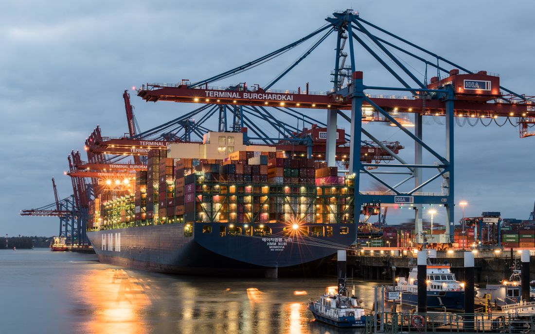 Stacked shipping containers seen from above at a port terminal.