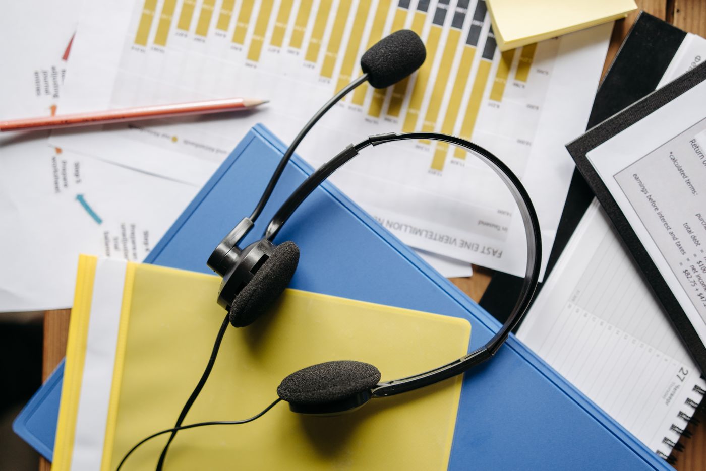 A telephone headset resting on a desk beside a keyboard.