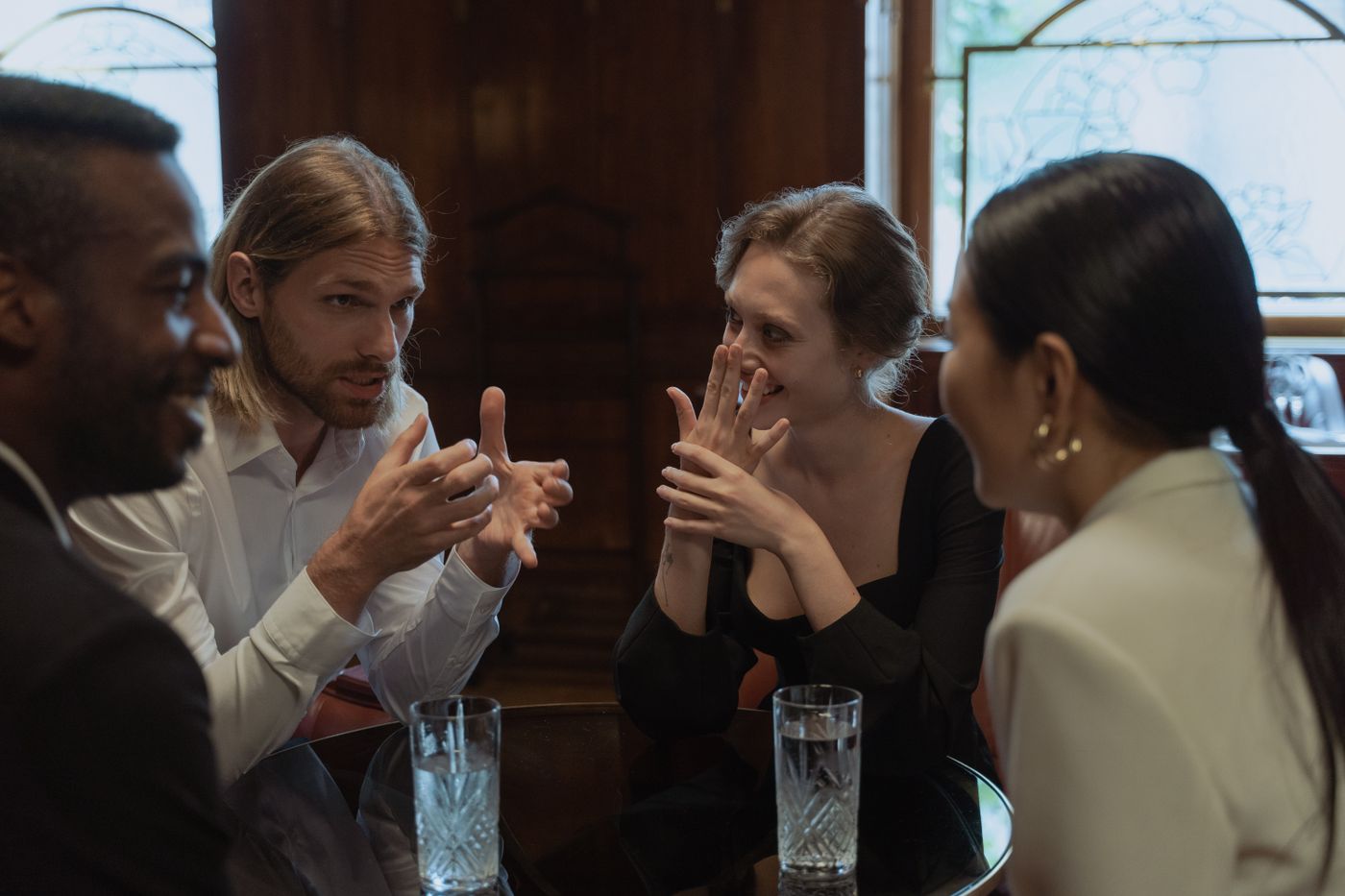 Four people around a table, one of them explaining something with his hands while the others listen.