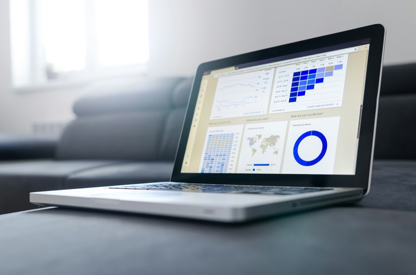 Printed charts and analytics reports spread across a desk beside a laptop.